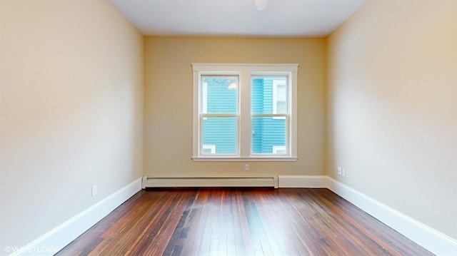 spare room featuring a baseboard heating unit and dark hardwood / wood-style floors