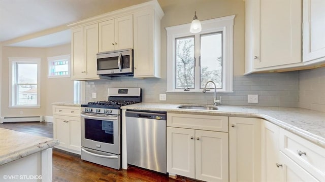 kitchen featuring a baseboard radiator, sink, backsplash, light stone counters, and stainless steel appliances