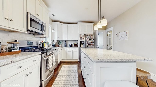 kitchen with decorative light fixtures, backsplash, a center island, light stone counters, and stainless steel appliances