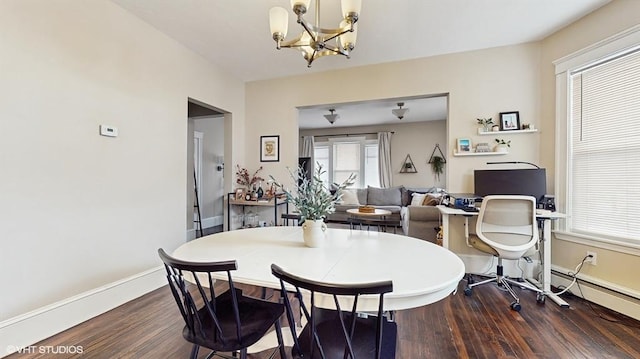 dining area featuring dark wood-type flooring, baseboard heating, and a notable chandelier