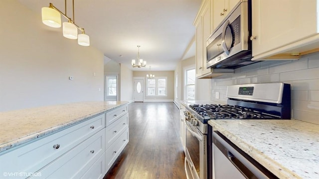 kitchen featuring light stone counters, appliances with stainless steel finishes, and decorative light fixtures