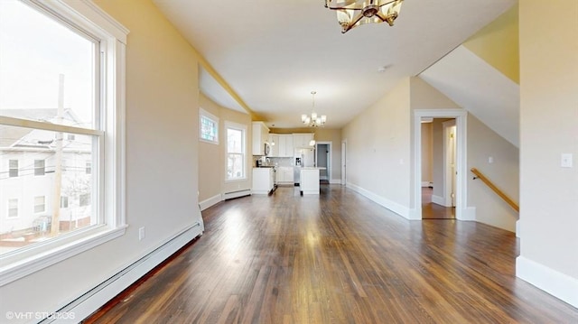 unfurnished living room with an inviting chandelier, a baseboard heating unit, and dark hardwood / wood-style floors