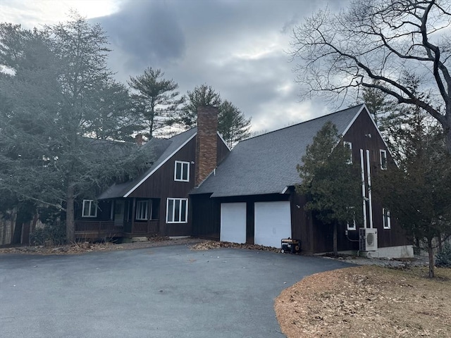 view of front of house with driveway, a chimney, and roof with shingles