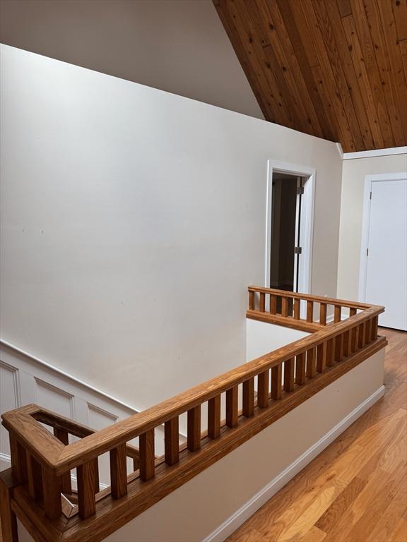 stairway featuring a decorative wall, a wainscoted wall, wood finished floors, wood ceiling, and vaulted ceiling