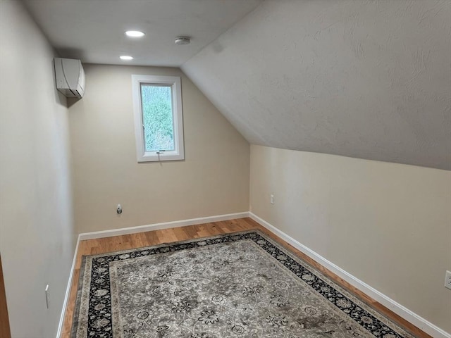 bonus room with lofted ceiling, recessed lighting, an AC wall unit, wood finished floors, and baseboards