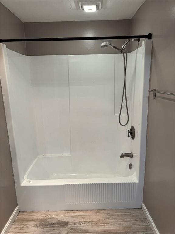 bathroom featuring baseboards, shower / bathtub combination, and wood finished floors