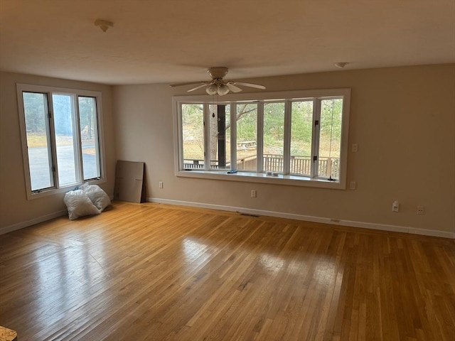 spare room featuring a ceiling fan, visible vents, baseboards, and hardwood / wood-style flooring