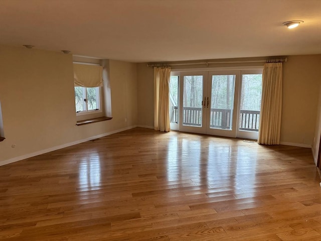 empty room featuring visible vents, baseboards, wood finished floors, and french doors