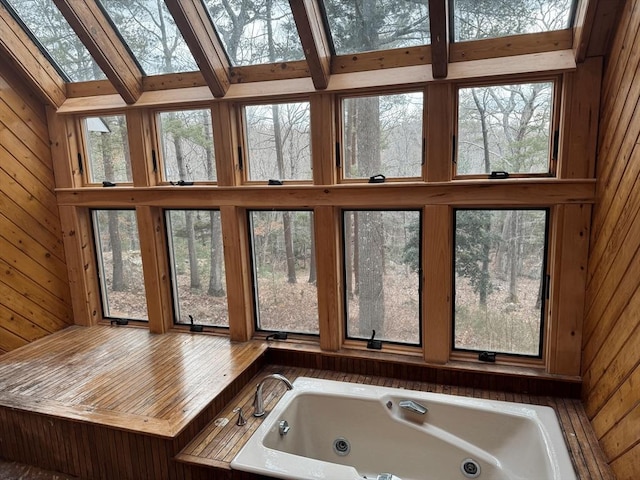 bathroom with a high ceiling, wood walls, a skylight, and a tub with jets