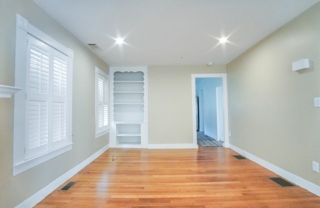 spare room featuring light wood-type flooring and built in features