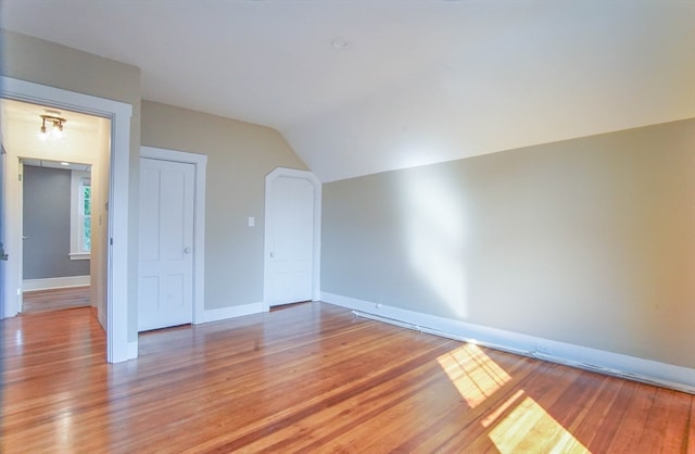 unfurnished room featuring wood-type flooring and lofted ceiling