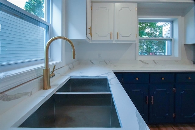 kitchen with light stone counters, sink, dark hardwood / wood-style flooring, and white cabinetry