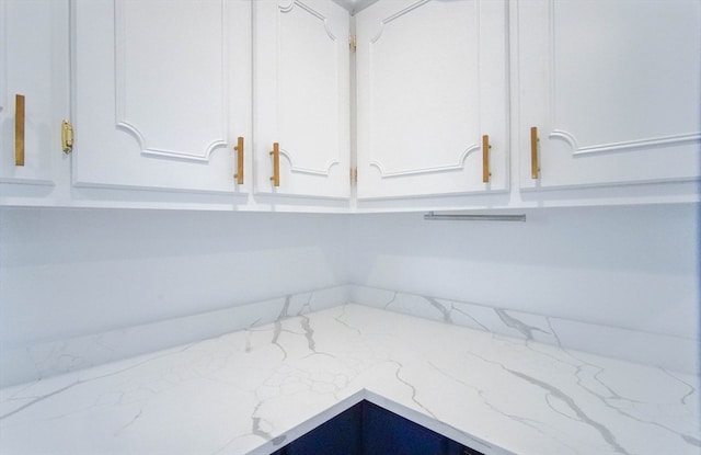 interior details featuring light stone countertops and white cabinetry