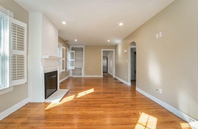 unfurnished living room with light hardwood / wood-style flooring and built in features