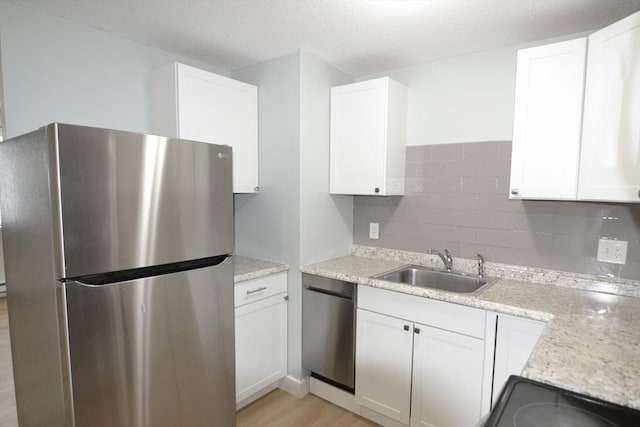 77 Nicholas Rd Unit I, Framingham, MA 01701 - kitchen with appliances with stainless steel finishes, a sink, decorative backsplash, white cabinetry, and light wood-style flooring