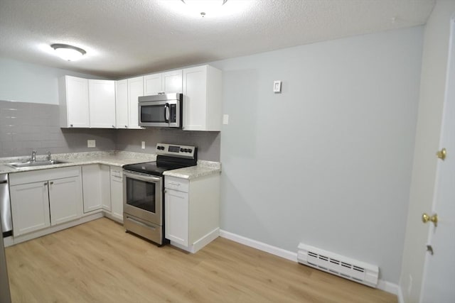 77 Nicholas Rd Unit I, Framingham, MA 01701 - kitchen with stainless steel appliances, a baseboard radiator, a sink, light wood-style flooring, and decorative backsplash