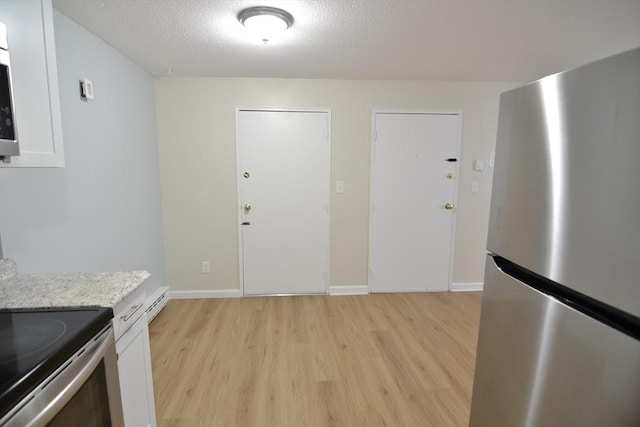 77 Nicholas Rd Unit I, Framingham, MA 01701 - kitchen featuring stainless steel appliances, light wood-type flooring, a textured ceiling, white cabinets, and baseboards