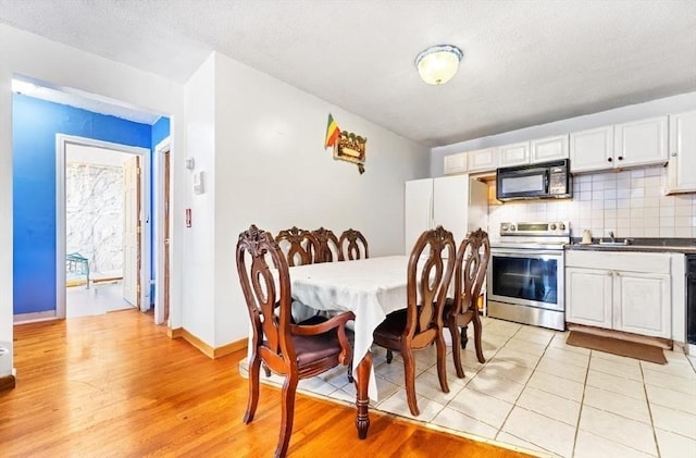 dining space featuring a textured ceiling, light hardwood / wood-style floors, and sink