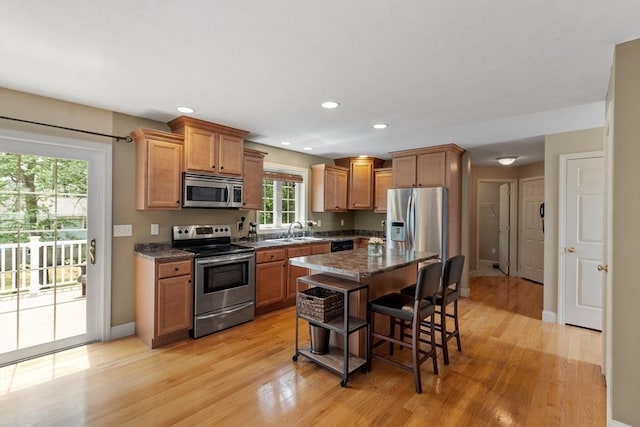 65 Saint Anthony St, Fitchburg, MA 01420 - kitchen with stainless steel appliances, a sink, light wood finished floors, a kitchen breakfast bar, and baseboards