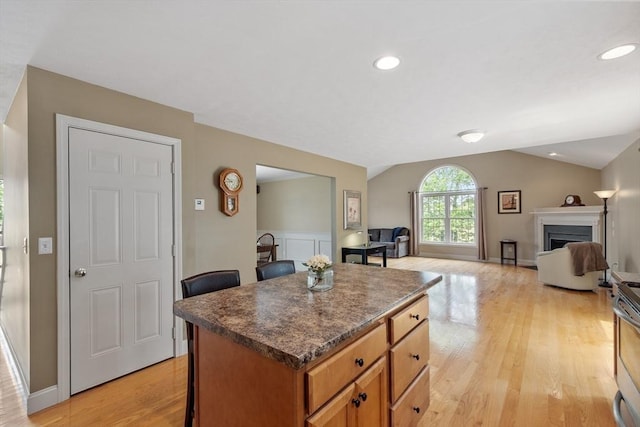 65 Saint Anthony St, Fitchburg, MA 01420 - kitchen with open floor plan, a breakfast bar area, vaulted ceiling, a center island, and light wood-style floors