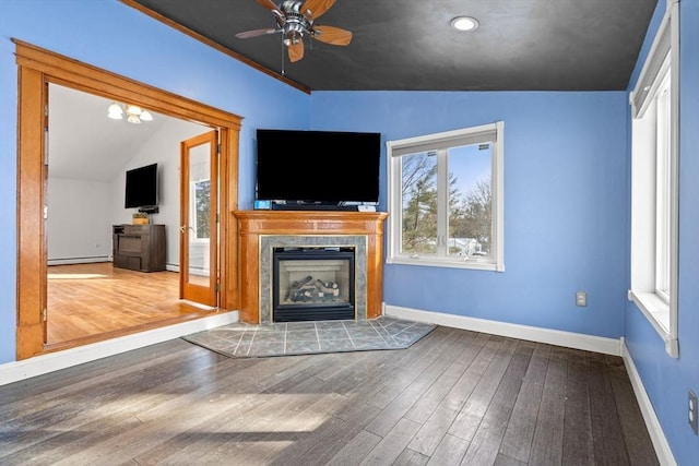 unfurnished living room with lofted ceiling, baseboards, a tiled fireplace, and wood finished floors