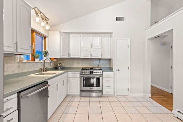 kitchen with baseboard heating, appliances with stainless steel finishes, white cabinetry, vaulted ceiling, and a sink