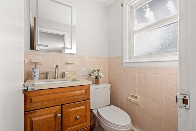 bathroom featuring toilet, vanity, and tile walls