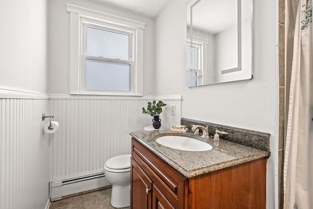 bathroom with toilet, a wainscoted wall, tile patterned floors, vanity, and a baseboard heating unit