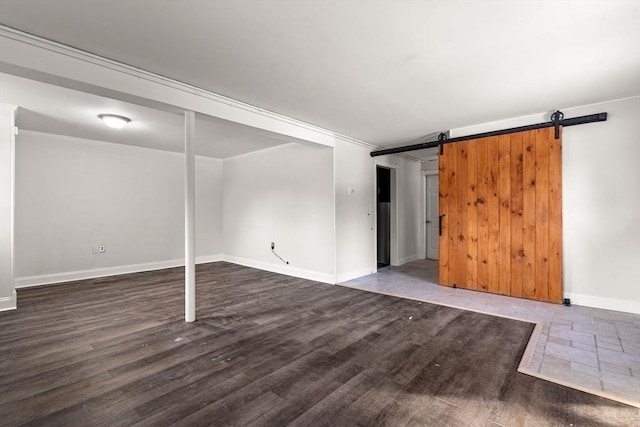 interior space featuring dark wood-style floors, baseboards, and a barn door