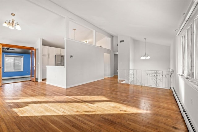 unfurnished living room with high vaulted ceiling, a baseboard heating unit, visible vents, light wood finished floors, and an inviting chandelier