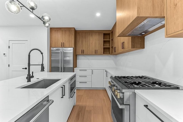 kitchen featuring high end appliances, a sink, light countertops, open shelves, and recessed lighting