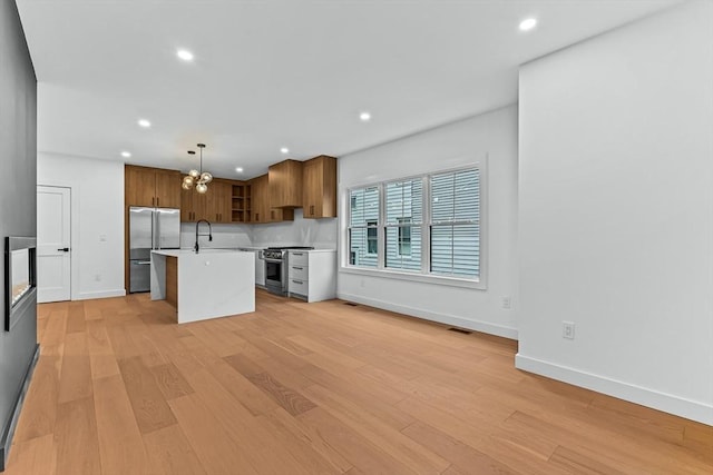 kitchen featuring high end appliances, light countertops, brown cabinets, recessed lighting, and a kitchen island with sink