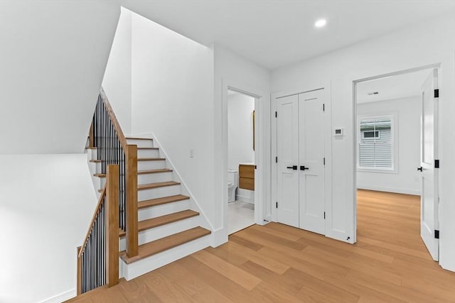 stairway featuring wood finished floors, recessed lighting, and baseboards