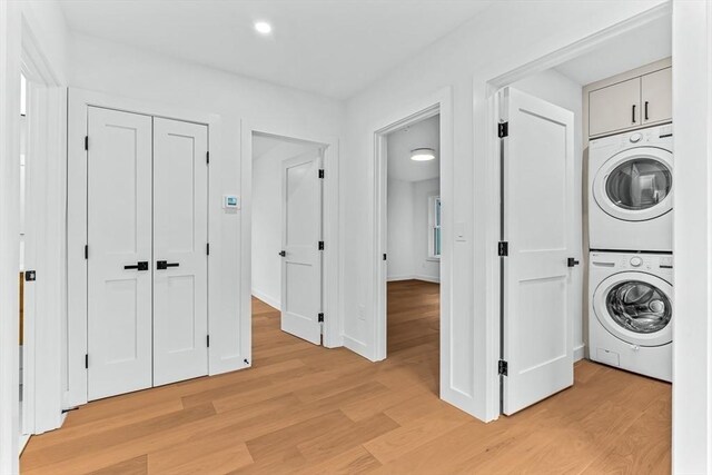 laundry area featuring stacked washer / drying machine, light wood-type flooring, recessed lighting, and baseboards
