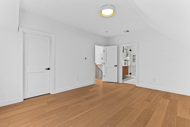 unfurnished bedroom featuring light wood-type flooring, baseboards, and connected bathroom