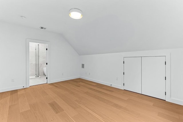 additional living space featuring light wood-type flooring, vaulted ceiling, and baseboards
