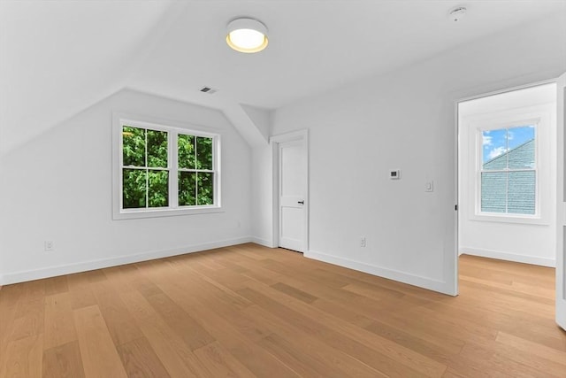 additional living space featuring light wood finished floors, vaulted ceiling, and baseboards