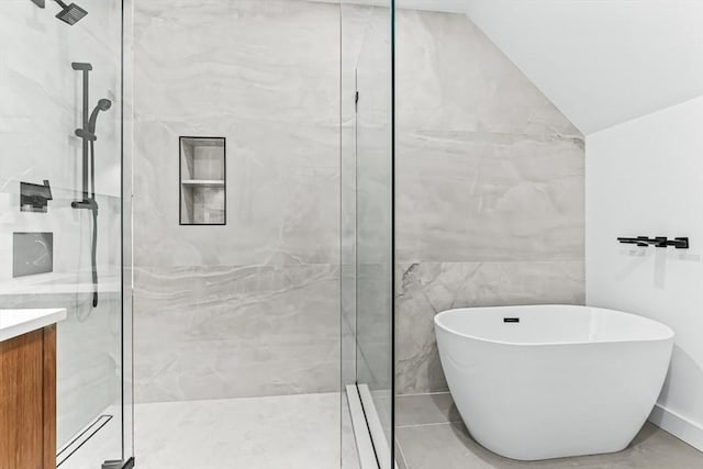 bathroom with a marble finish shower, a soaking tub, vanity, and vaulted ceiling