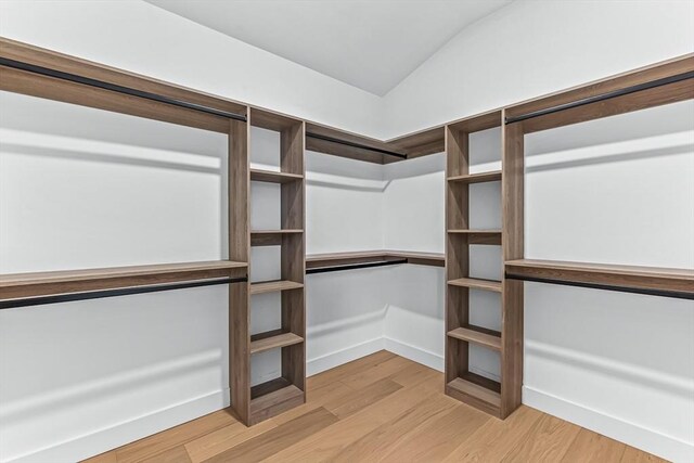 walk in closet featuring light wood-style flooring and lofted ceiling