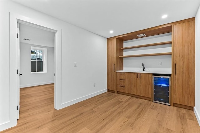 indoor wet bar featuring beverage cooler, light wood-type flooring, baseboards, and recessed lighting