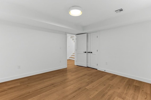 unfurnished room with baseboards, light wood-type flooring, and stairway