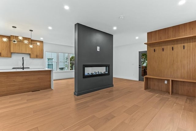 kitchen featuring light wood-style floors, brown cabinets, light countertops, recessed lighting, and decorative light fixtures