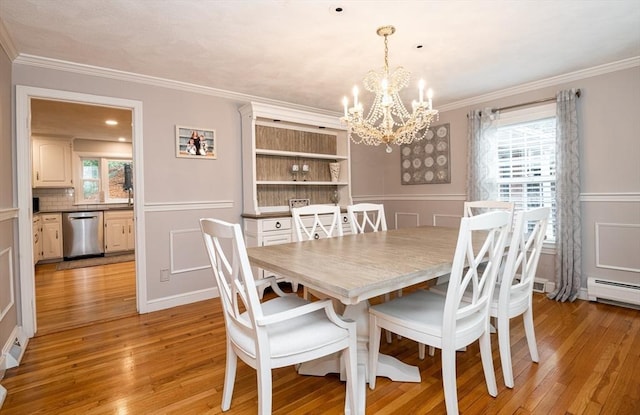 dining room with ornamental molding, a chandelier, and light hardwood / wood-style floors