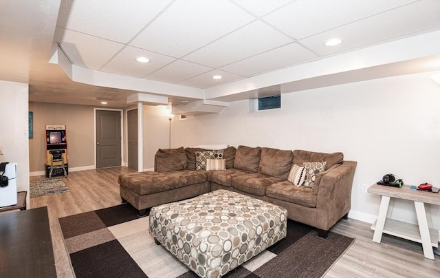 living room with a paneled ceiling and light wood-type flooring