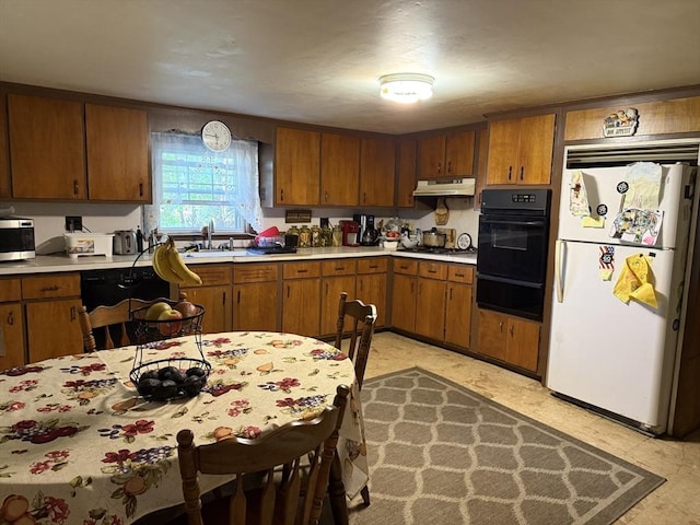kitchen featuring a sink, black appliances, a warming drawer, under cabinet range hood, and light countertops