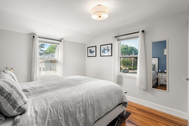bedroom with wood finished floors, vaulted ceiling, and baseboards