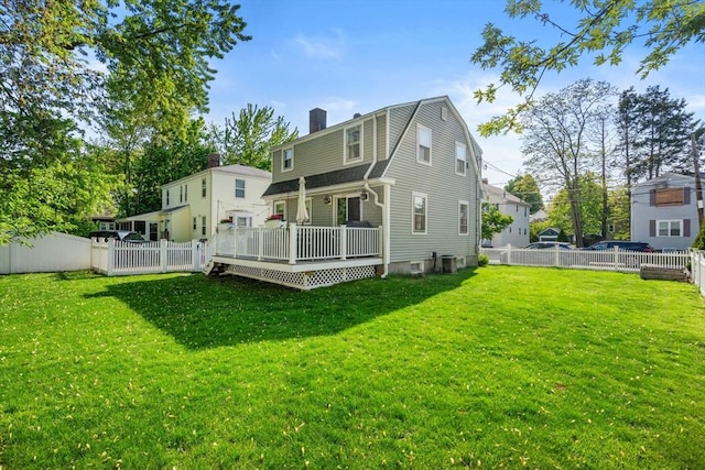 rear view of property with a chimney, a gambrel roof, a deck, and central AC