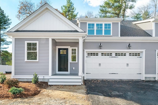 view of front of property featuring driveway, roof with shingles, an attached garage, and board and batten siding