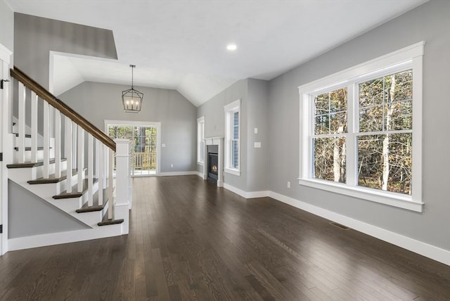 foyer featuring dark wood finished floors, visible vents, a lit fireplace, baseboards, and stairs