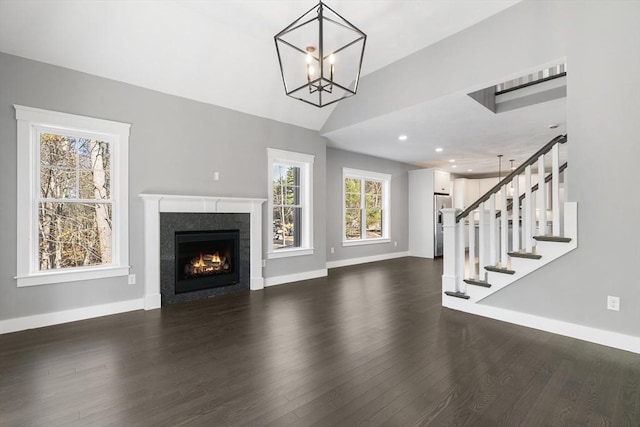 unfurnished living room with dark wood-style floors, lofted ceiling, stairway, and baseboards